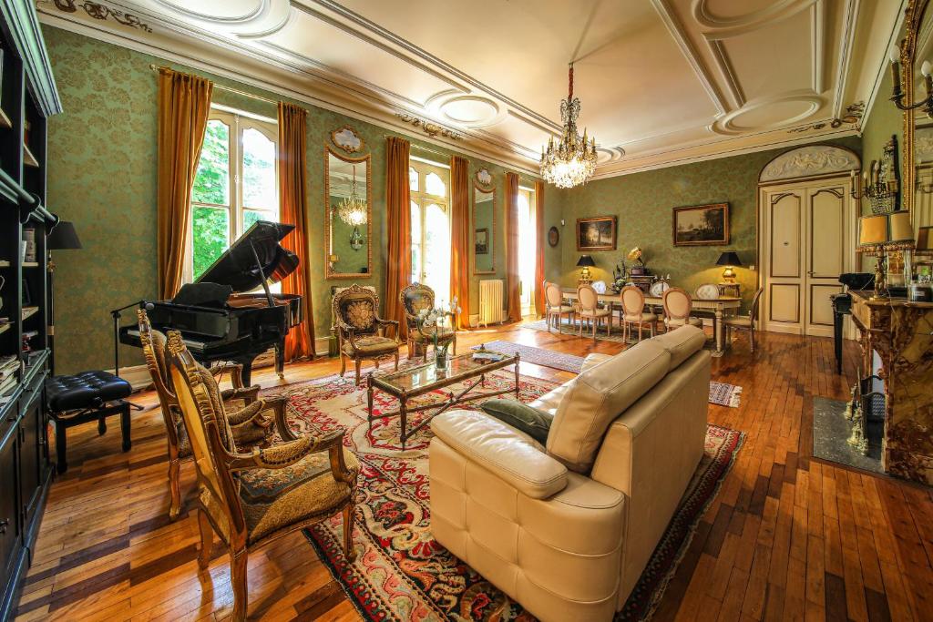 a living room with a couch and a piano at Le Manoir du Thouron in Saint-Sulpice
