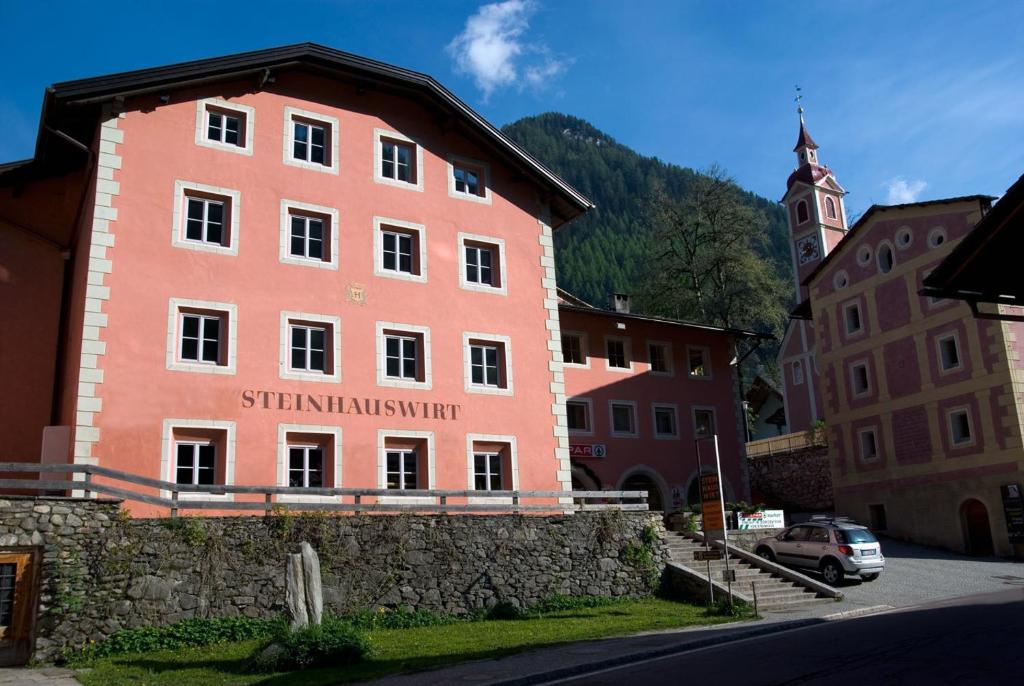 a large pink building in a town with a church at Steinhauswirt in Cadipietra