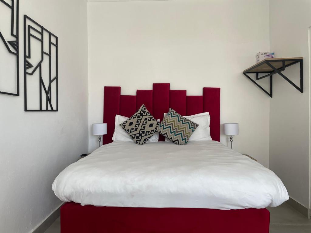 a bedroom with a large bed with a red headboard at 15 On Burns Guesthouse in Cape Town