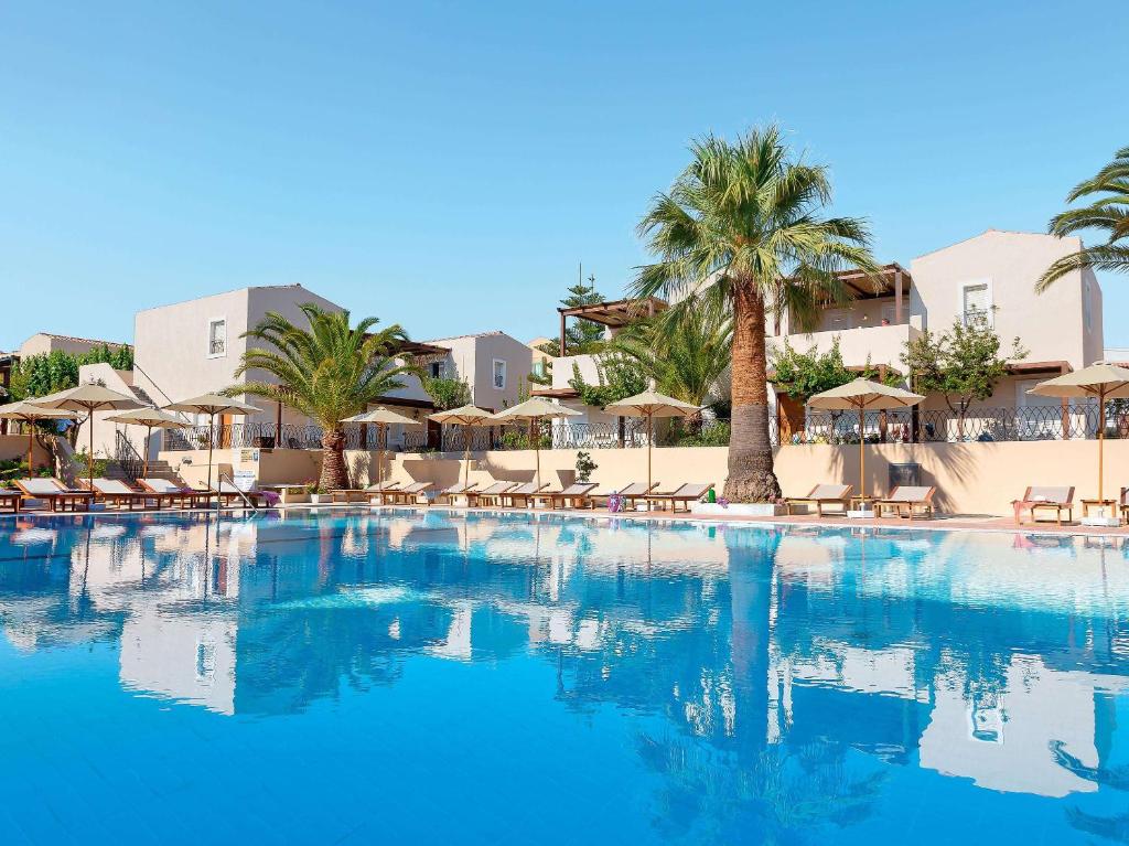uma grande piscina com cadeiras e palmeiras em Grand Leoniki Residence by Grecotel em Platanes