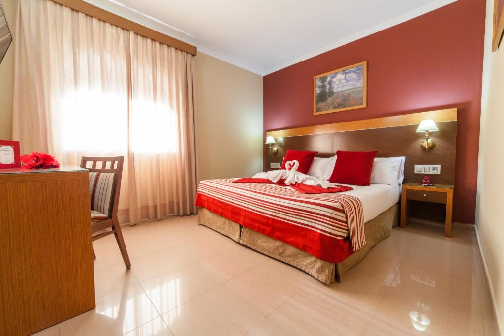 1 dormitorio con 1 cama grande con almohadas rojas en Hotel Regio 2, en Cádiz
