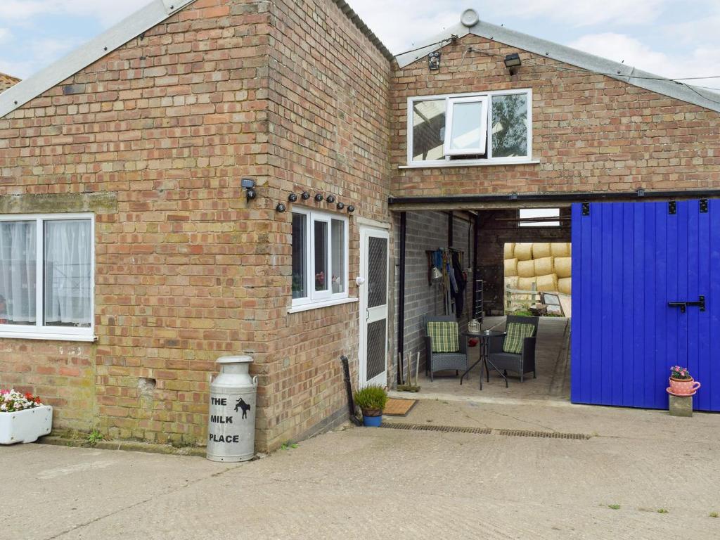 ein Backsteinhaus mit blauer Garage in der Unterkunft The Milk Place in Harby