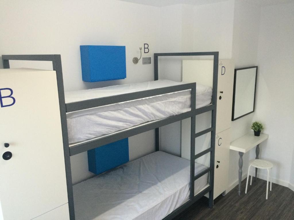 a room with two bunk beds and a desk at Chameleon Youth Hostel Alicante in Alicante