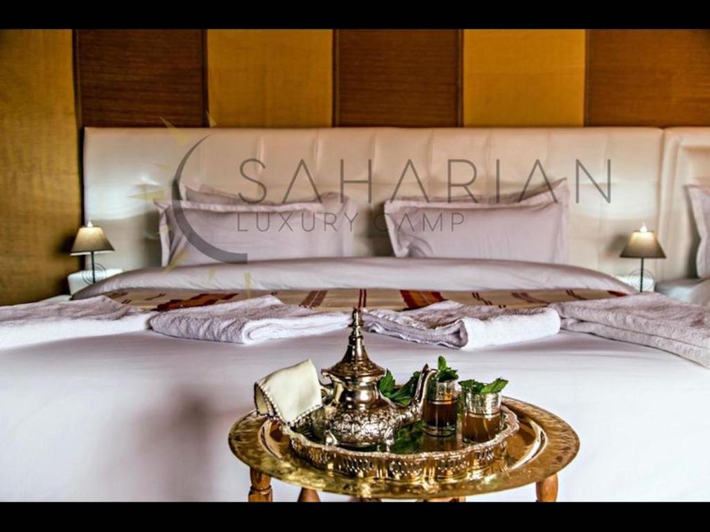Un dormitorio con una cama grande y una mesa enfrente. en Room in Bungalow - Saharian Luxury Camp, en Tisserdmine