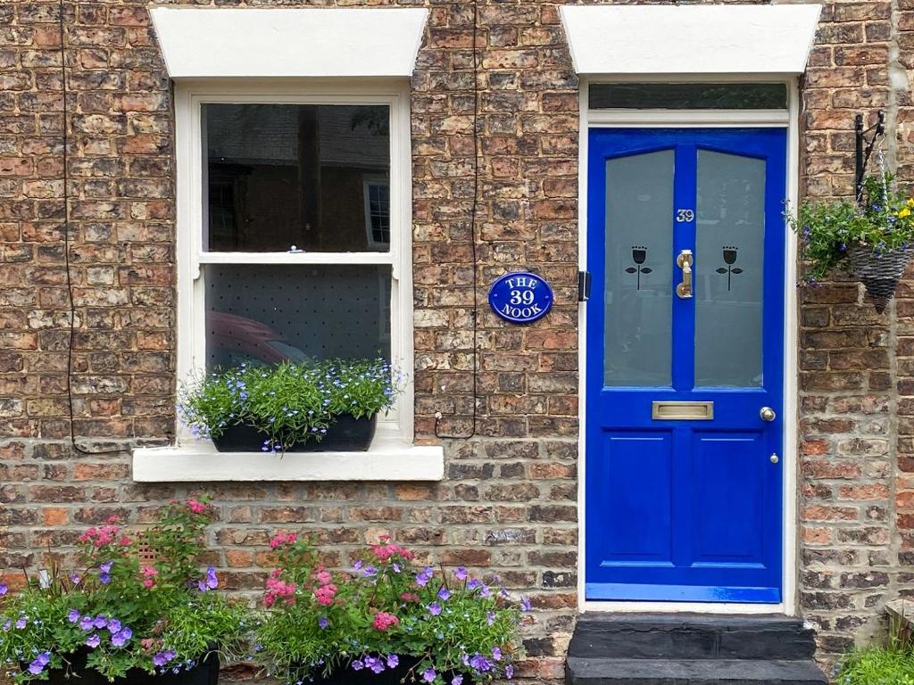 a blue door on a brick house with flowers at The Nook in Thirsk