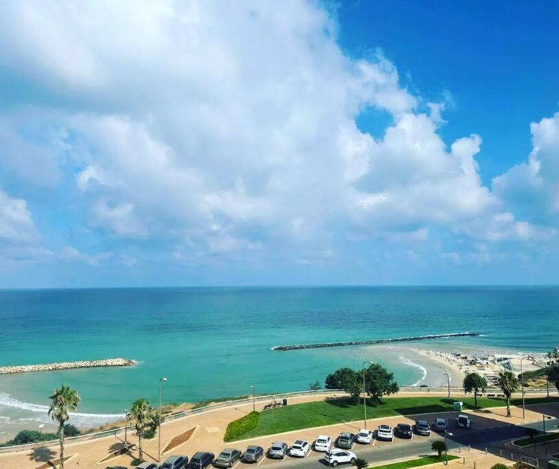 a view of a beach and a parking lot with cars at Beautiful 2-Bedroom Sea-View apartment in Netanya