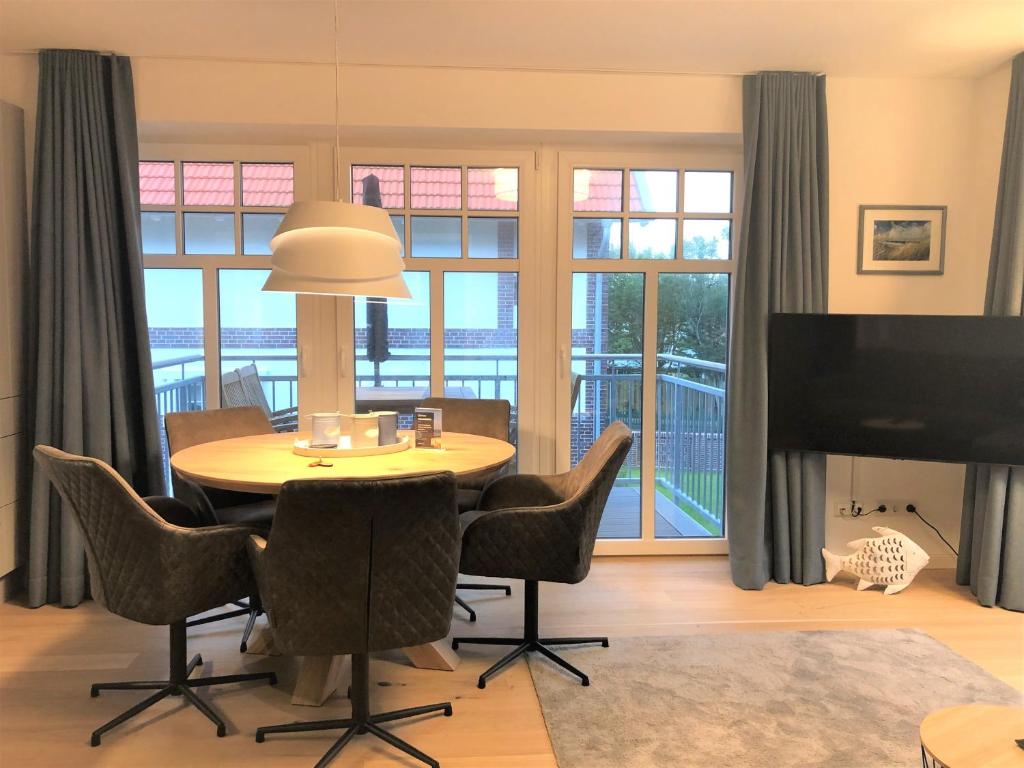 ein Wohnzimmer mit einem Tisch, Stühlen und einem TV in der Unterkunft Ferienwohnung Inselherz in Wangerooge