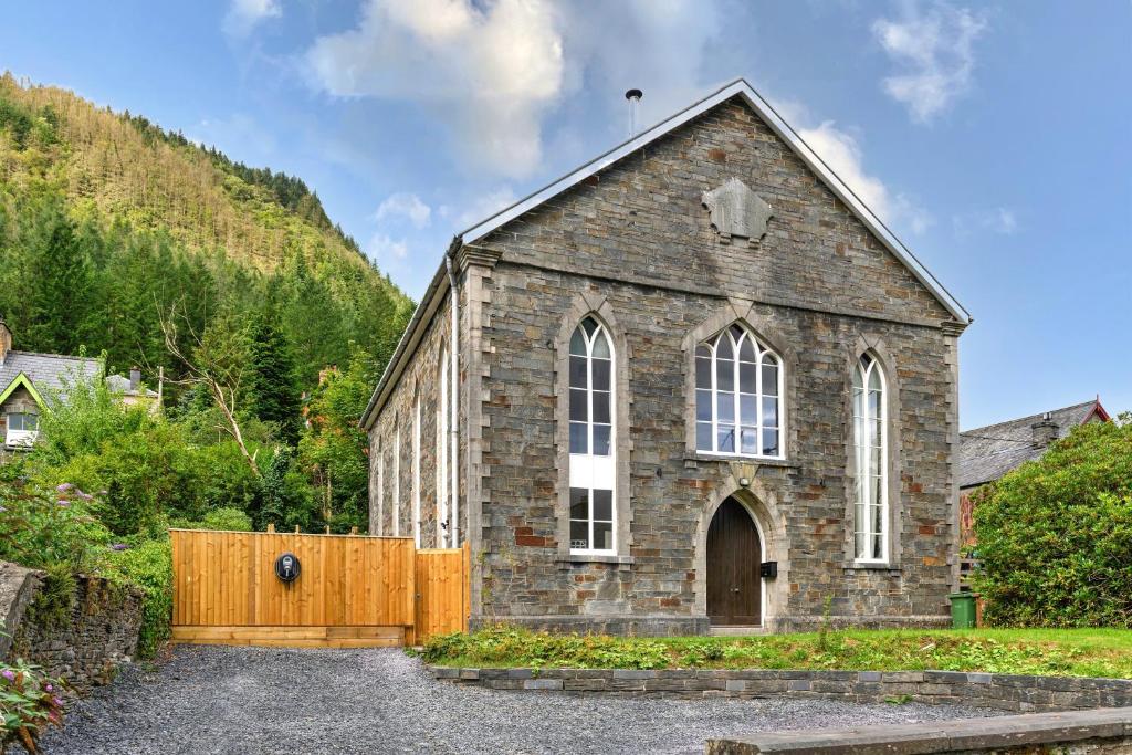 an old stone church with a wooden fence at Finest Retreats - Luxury Converted Chapel with Hot Tub & Games Room in Dinas Mawddwy