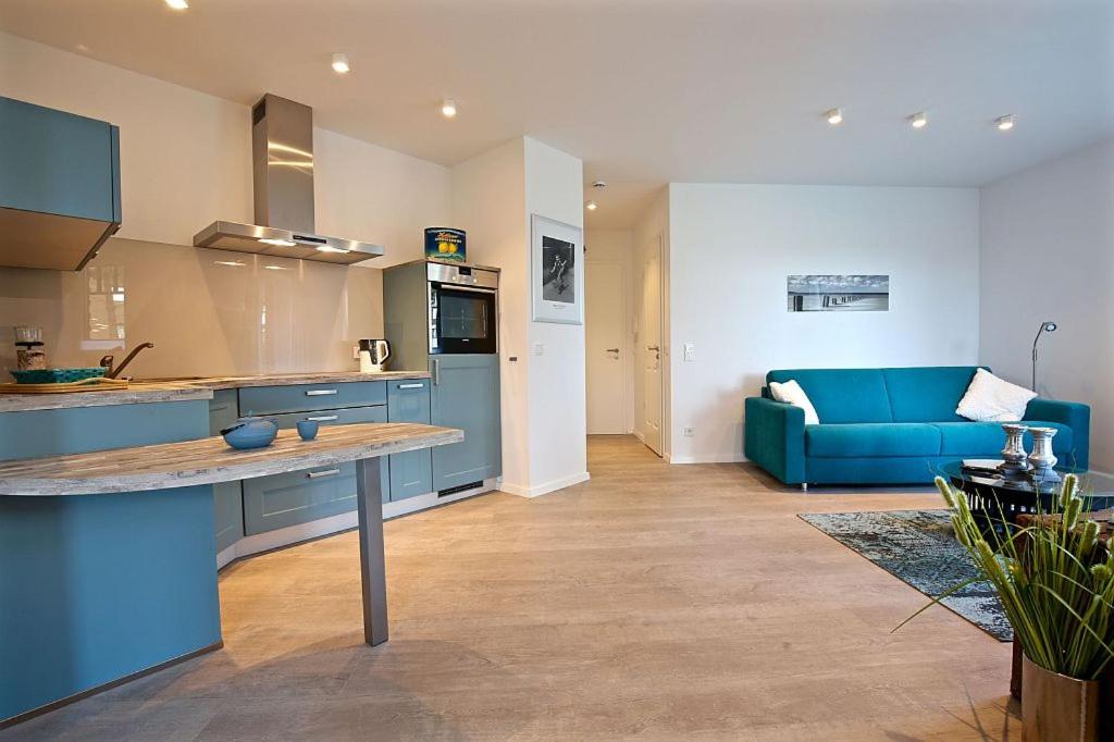a kitchen and a living room with a blue couch at Ferienwohnung Dünenperle in Wangerooge