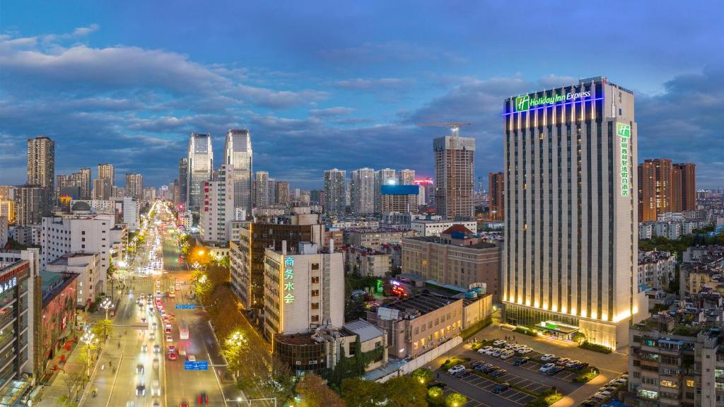 Holiday Inn Express Kunming West, an IHG Hotel في كونمينغ: أفق المدينة في الليل مع مبنى طويل