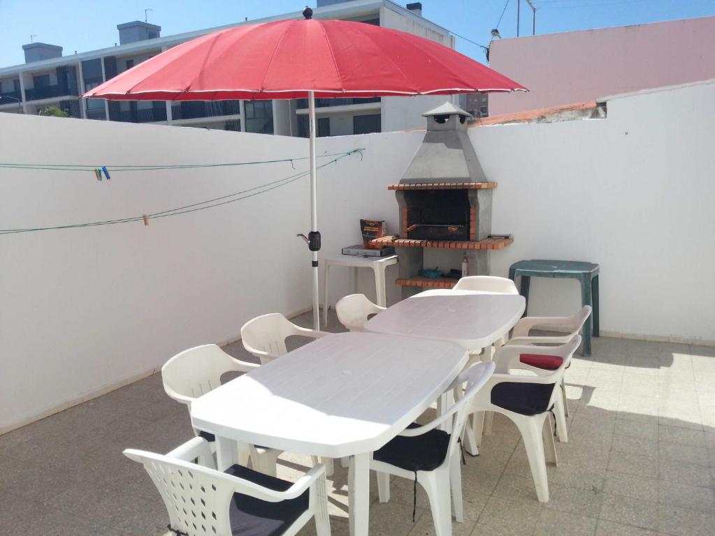 een tafel en stoelen met een rode parasol op een dak bij Casa Rosa in Monte Gordo
