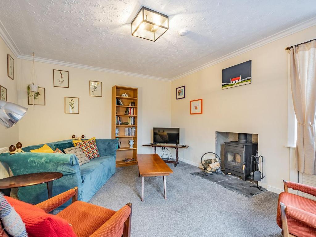 a living room with a blue couch and a fireplace at Black Grouse in Culter