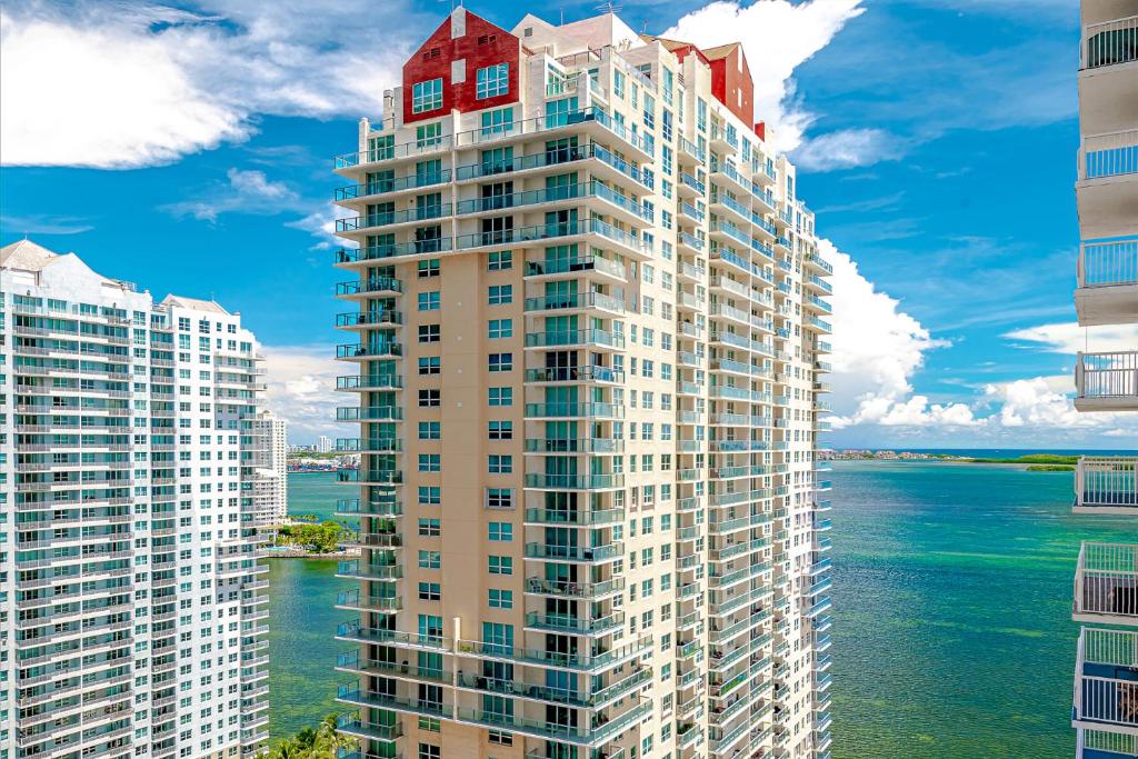 a tall building with a red roof next to the water at Miami condo with city & ocean views! Sleep up to 6! in Miami