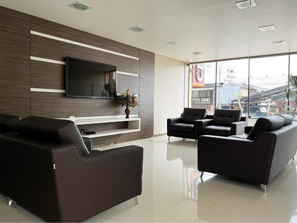 ein Wohnzimmer mit 2 Sofas und einem Flachbild-TV in der Unterkunft Tri Hotel Xanxerê in Xanxerê