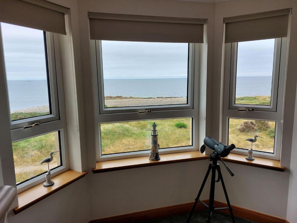 um quarto com três janelas com uma câmara num tripé em Aurora em Lossiemouth