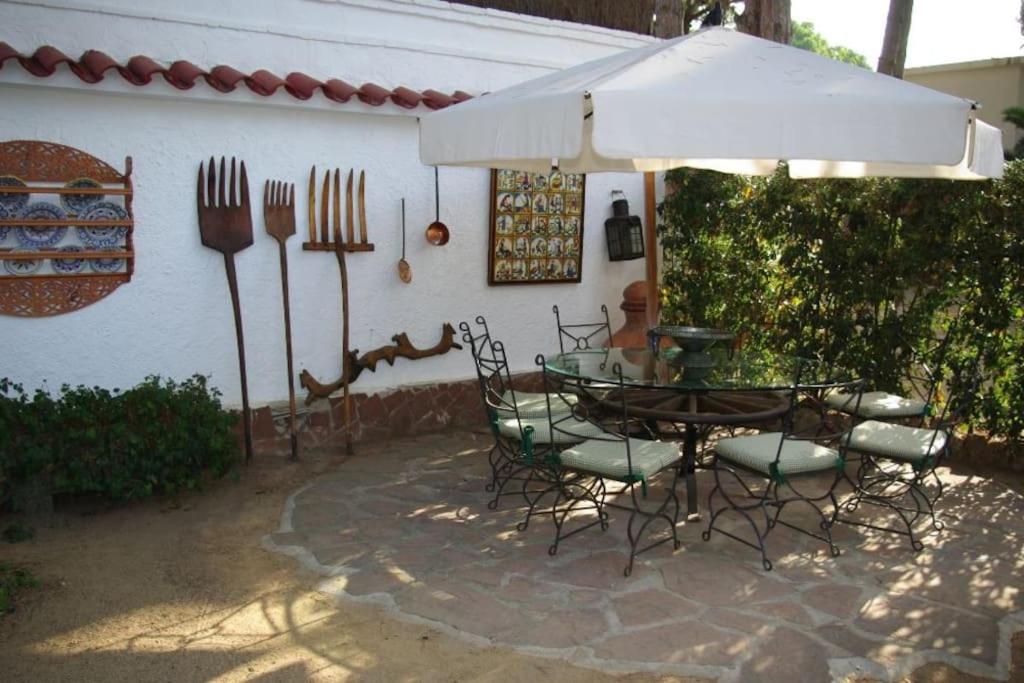 a patio with a table and chairs under an umbrella at Enjoy your holidays 300m to the Mediterranean sea at Villa DIVALI in Castelldefels