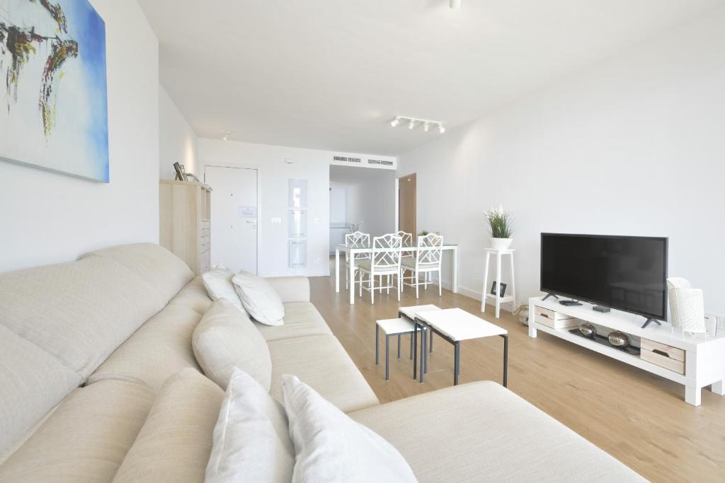 Biały salon z kanapą i telewizorem w obiekcie Apartamento de lujo con jardin privado w mieście Torrox Costa