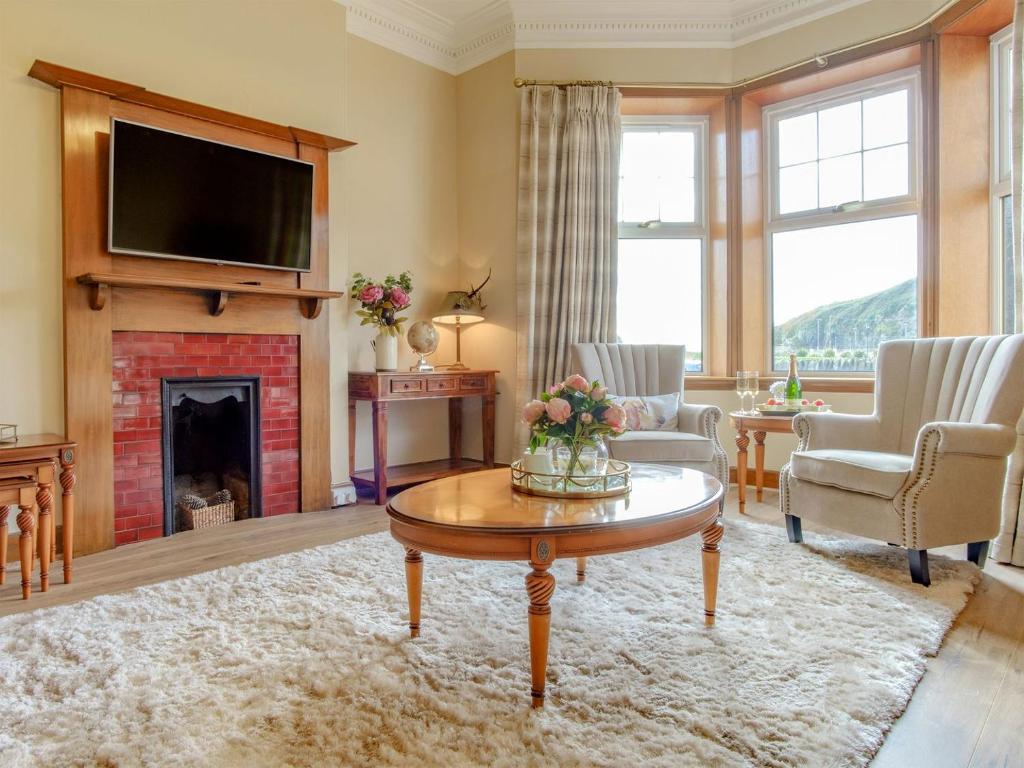 a living room with a fireplace and a tv at Blair Terrace in Portpatrick