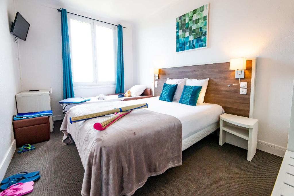 a hotel room with two beds and a window at La Villa Andry in Ouistreham