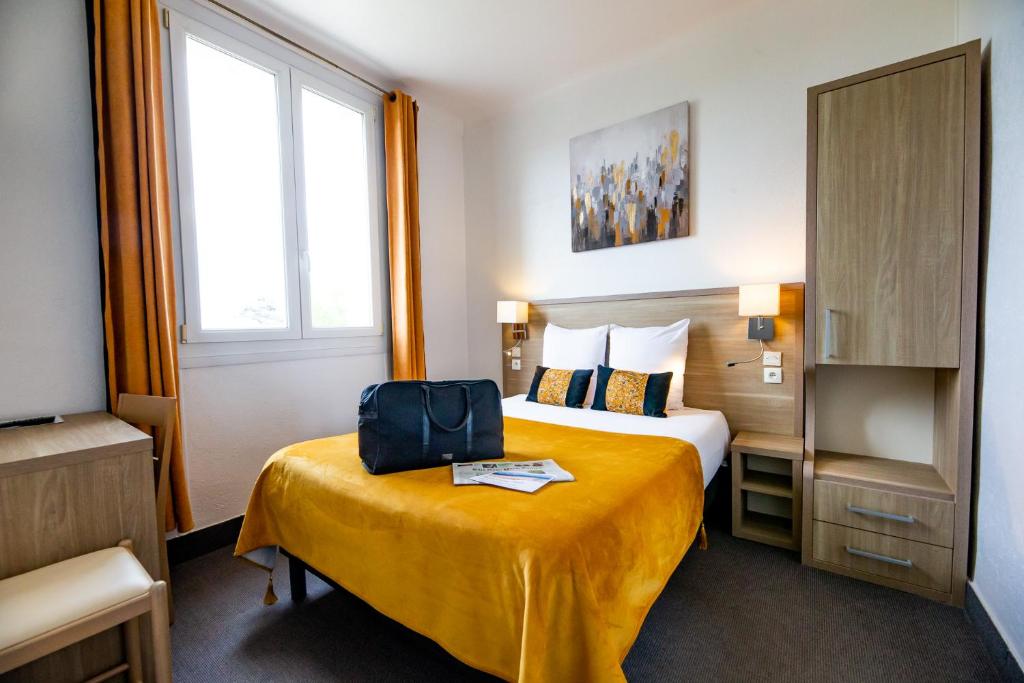 a hotel room with a bed with a suitcase on it at La Villa Andry in Ouistreham
