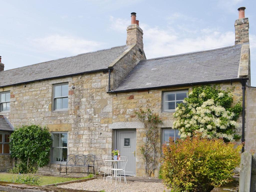 an old stone house with a table in front of it at Greenyard Cottage in Rothbury