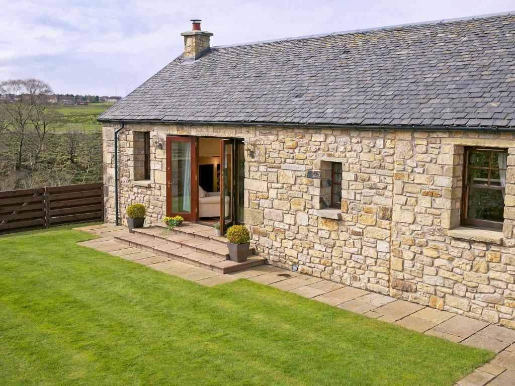 a stone house with a grass yard in front of it at The Bothy in Haywood