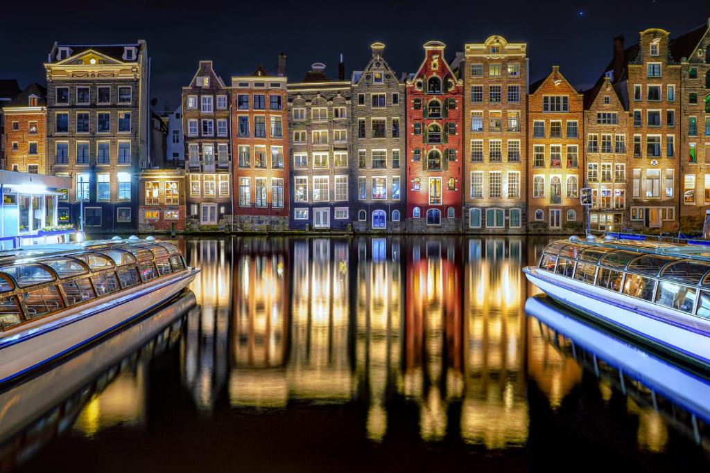 a group of buildings with lights on the water at night at Botel Lena Maria in Amsterdam