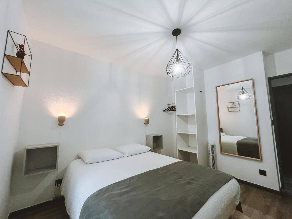 ein weißes Schlafzimmer mit einem Bett und einem Spiegel in der Unterkunft Appartement meublé 60m2 Le Drômardèchois ARDÈCHE -GESTLOC- in Tournon-sur-Rhône