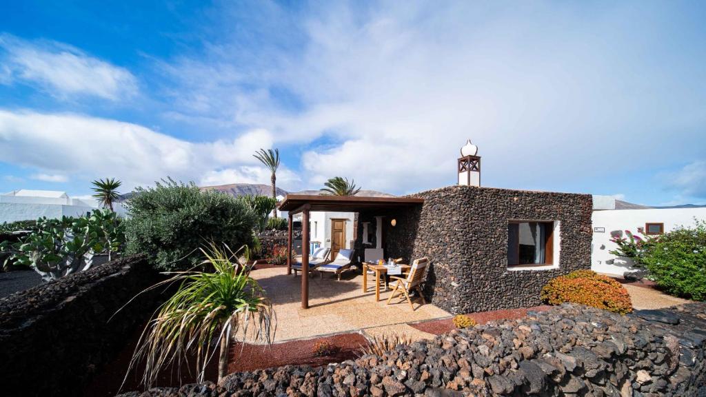Una casa de piedra con una mesa y sillas delante de ella. en Casa Margarita 3, en Mala