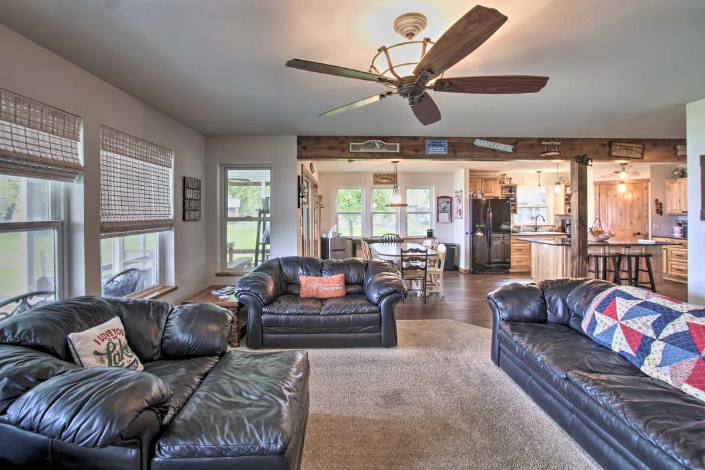 a living room with leather couches and a ceiling fan at Bright Shawano Lake Oasis - Walk to Boat Launch! in Shawano