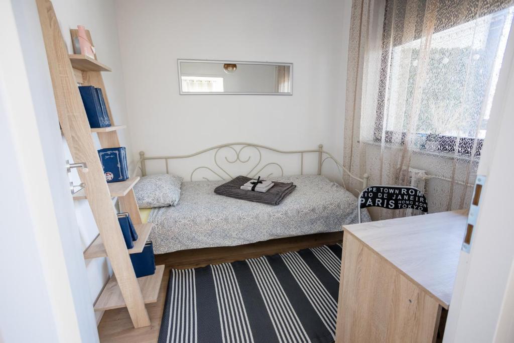a small bedroom with a bed and a window at Apartman "Stay In" Osijek in Osijek