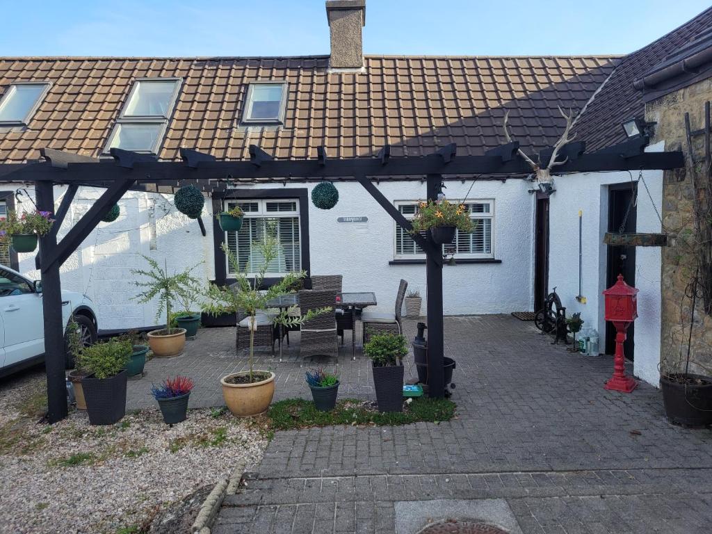 a pergola in front of a house with plants at Rooms at Tarrareoch in Bathgate