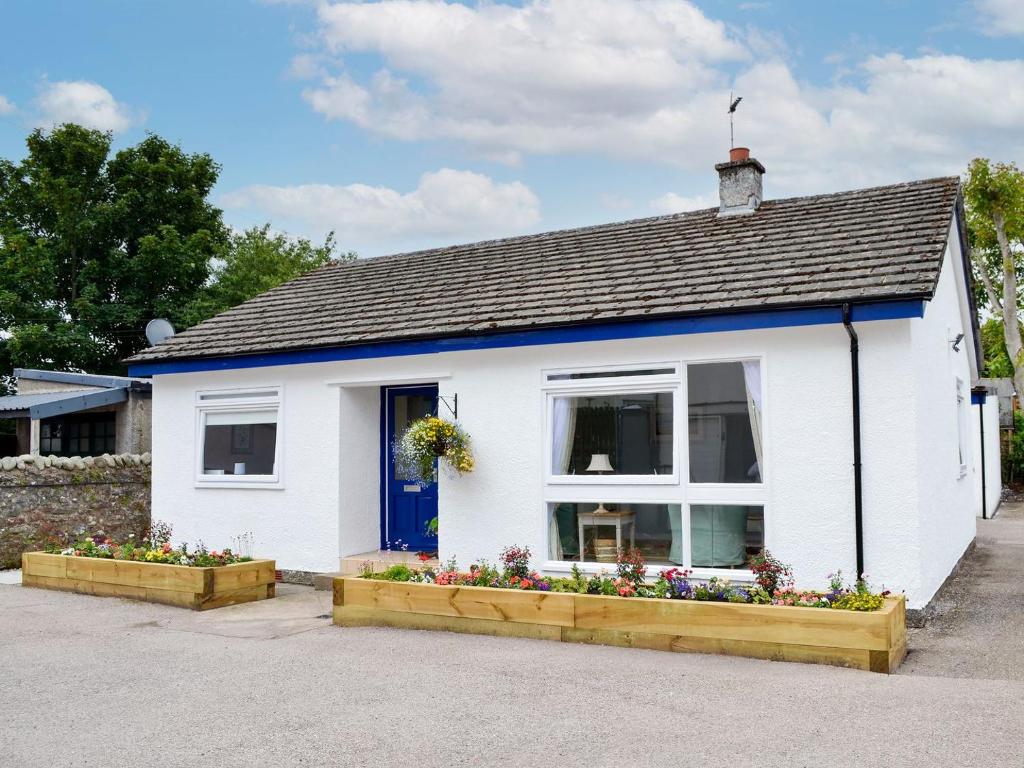 a white house with a blue door and windows at The Butchers Cottage in Edzell