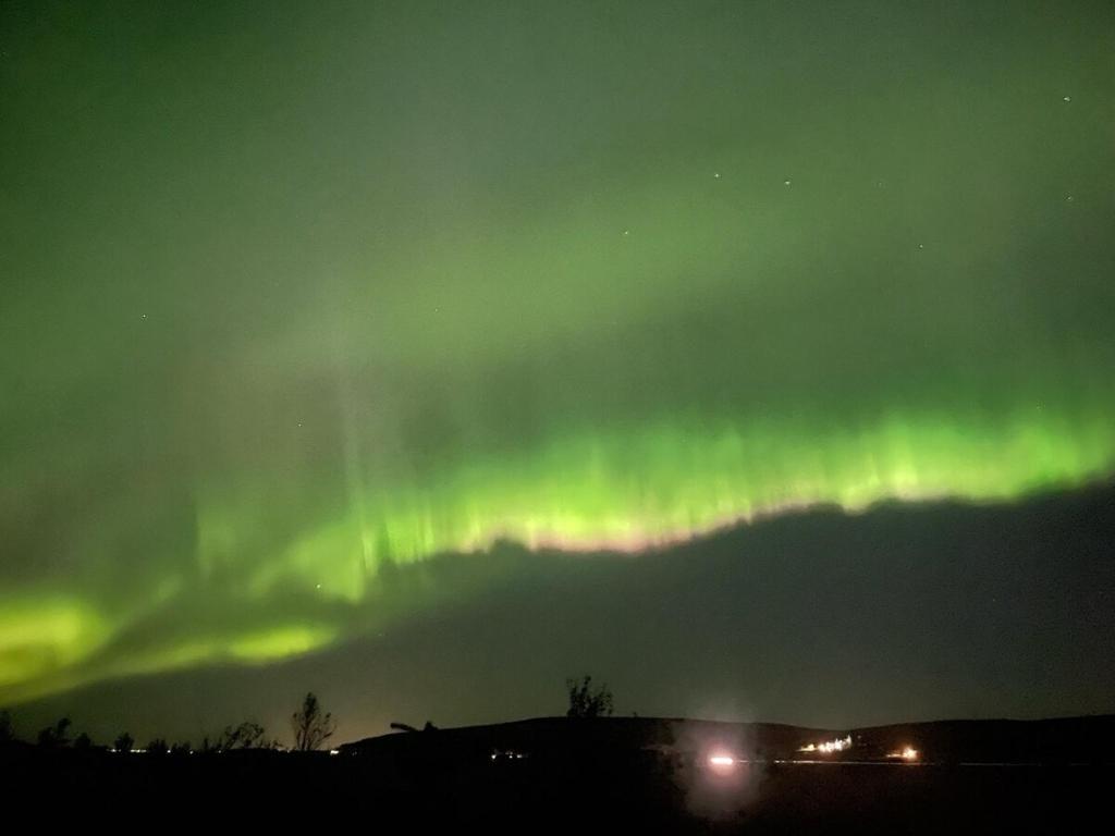 an aurora in the sky over a city at Adorable cosy and private new cabin in the south in Hvolsvöllur