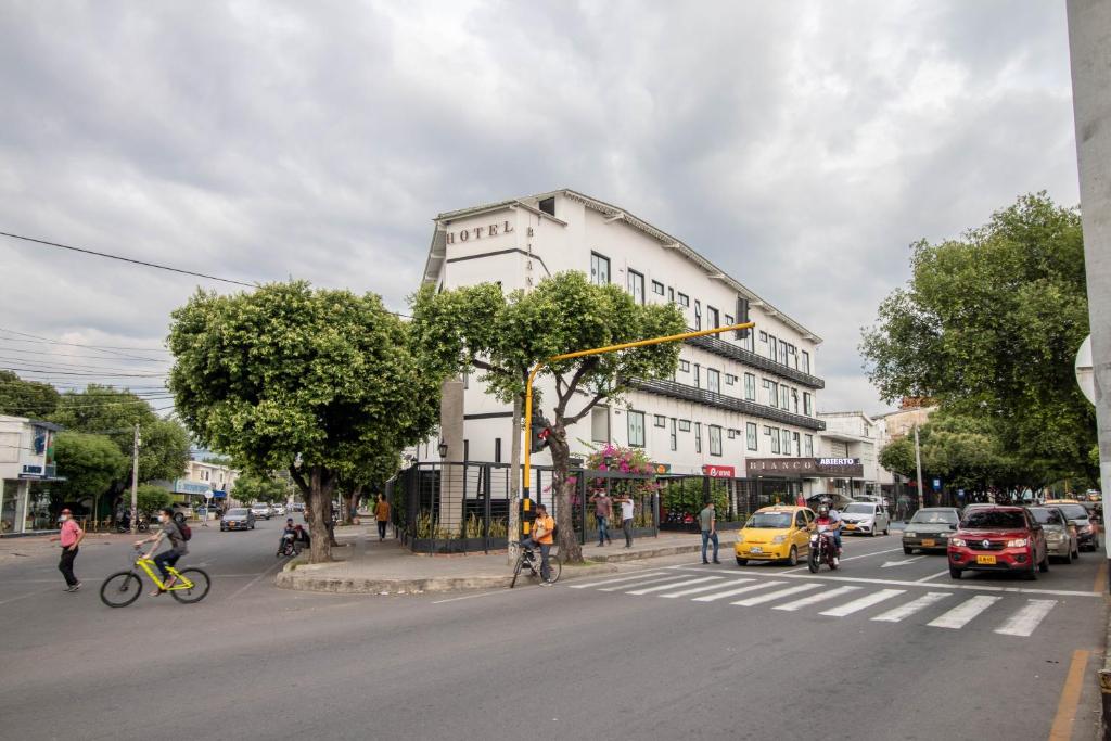 una calle con un edificio blanco y gente en bicicletas y coches en Bianco Hotel Boutique, en Cúcuta