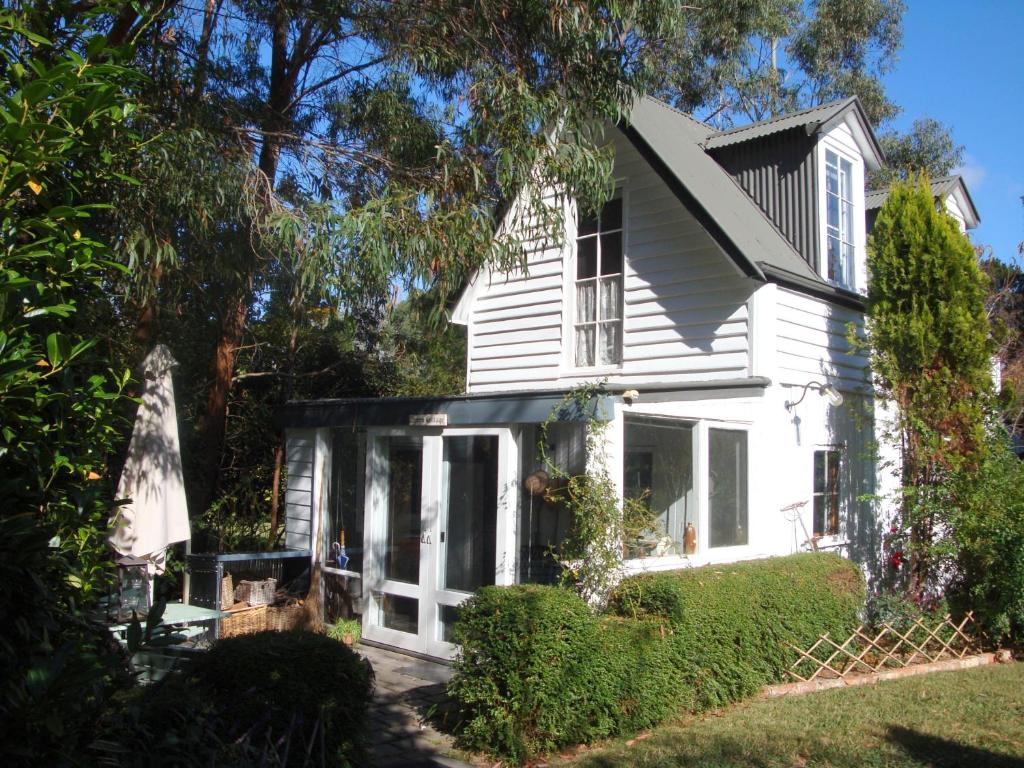 Casa blanca con puertas y ventanas blancas en Devon Cottage, en Bowral