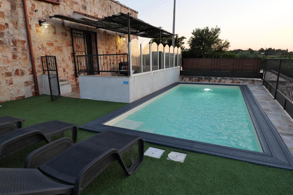 une grande piscine avec des chaises et une maison dans l'établissement Il borgodellequerce CASA ULIVI PISCINA PRIVATA, à Martina Franca