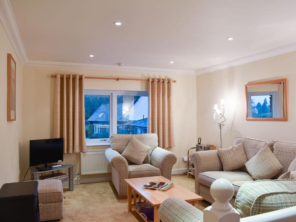 a living room with a couch and chairs and a tv at Woodside Cottage in Troutbeck Bridge