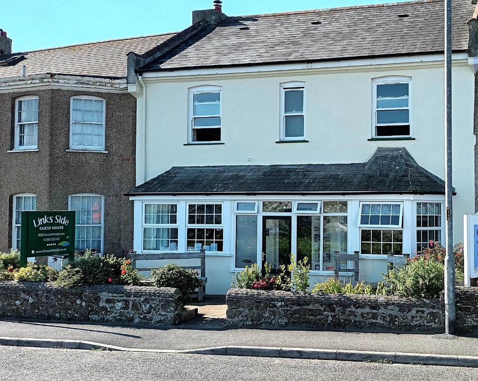 a white building with a sign in front of it at Links Side Guest House in Bude