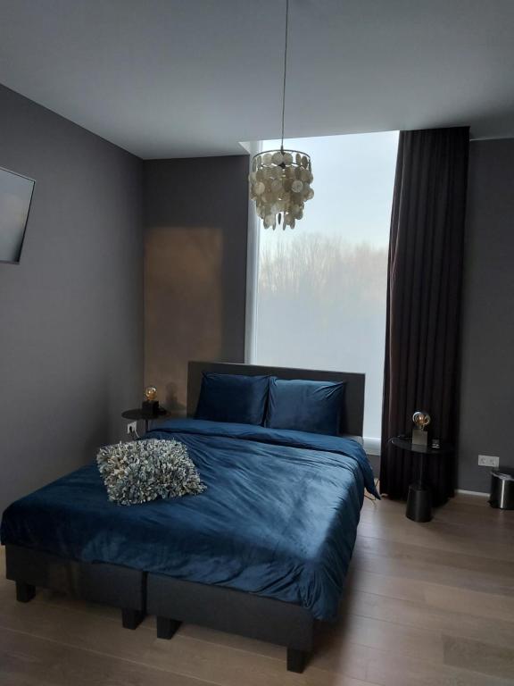 a bedroom with a blue bed and a large window at Bed & Wellness Boxtel, luxe kamer met airco en eigen badkamer in Boxtel