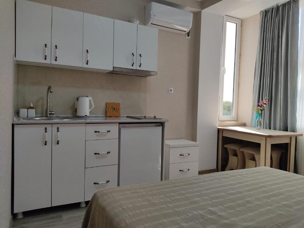 uma cozinha com armários brancos e uma cama num quarto em Pushkin street Pearl em Kutaisi