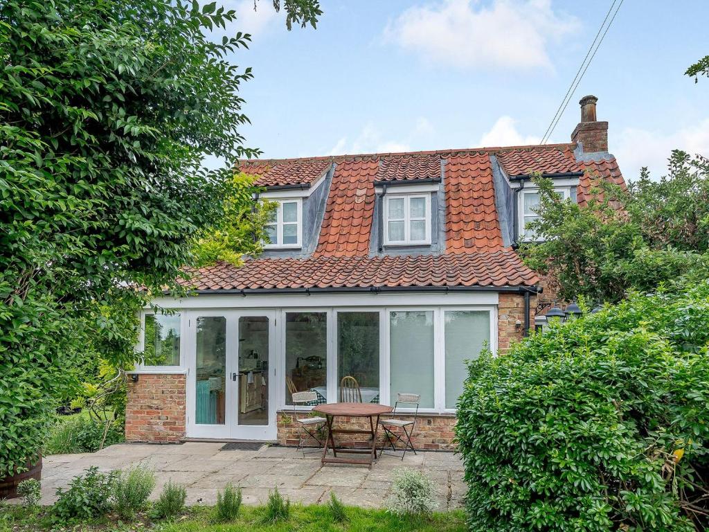 an extension to a brick house with a table and chairs at Jasmine Cottage in Hilgay