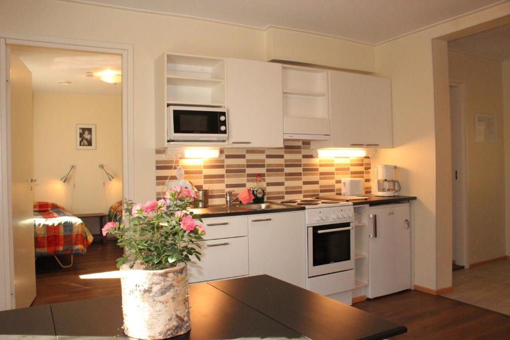 ロヴァニエミにあるHotel Aakenus Holiday Home Kokkiの白いキャビネットと花のテーブル付きのキッチンが備わります。