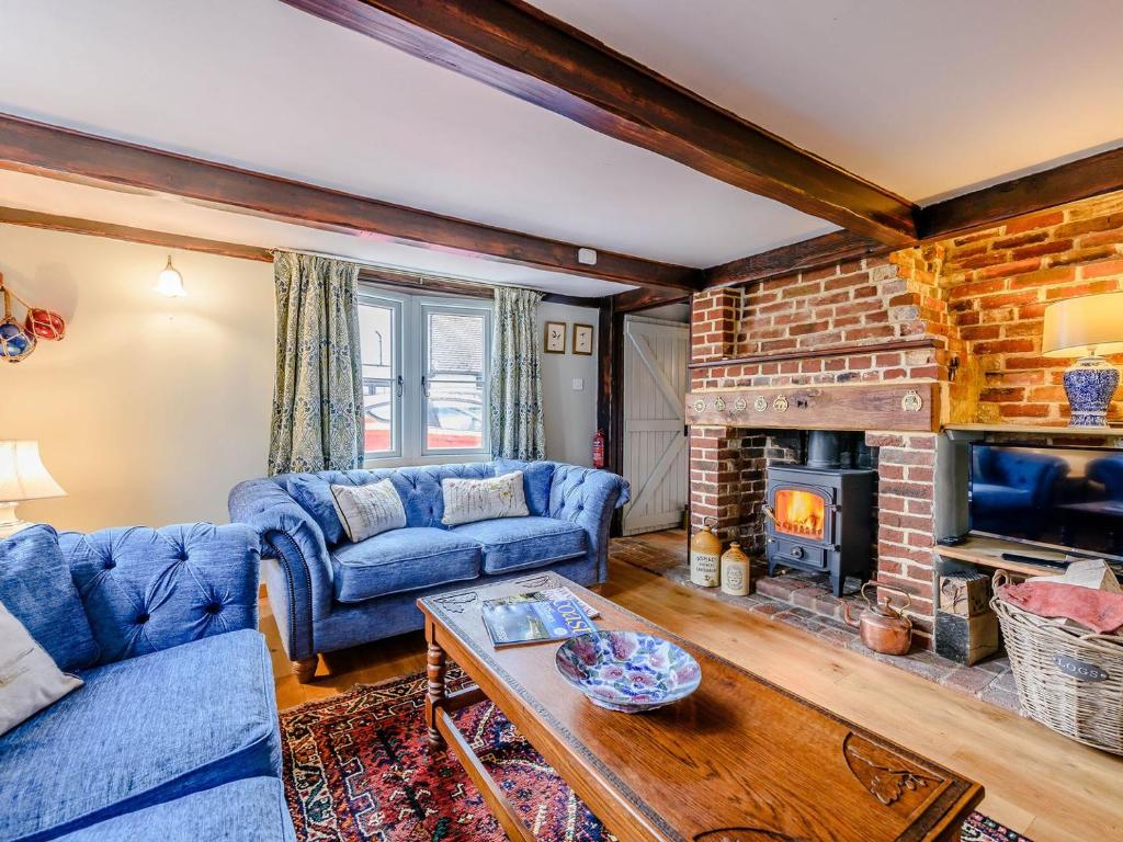 a living room with a blue couch and a fireplace at Sunny House By The Sea in Dymchurch