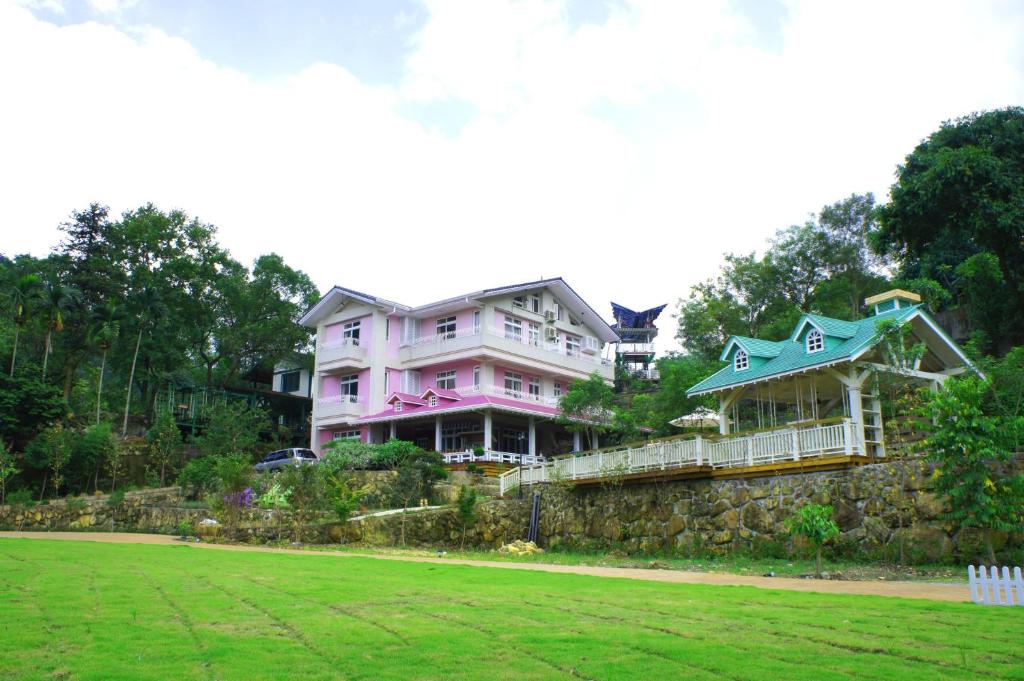 a large pink house on top of a stone wall at Bear Meets Moose Homestay B&amp;B in Puli