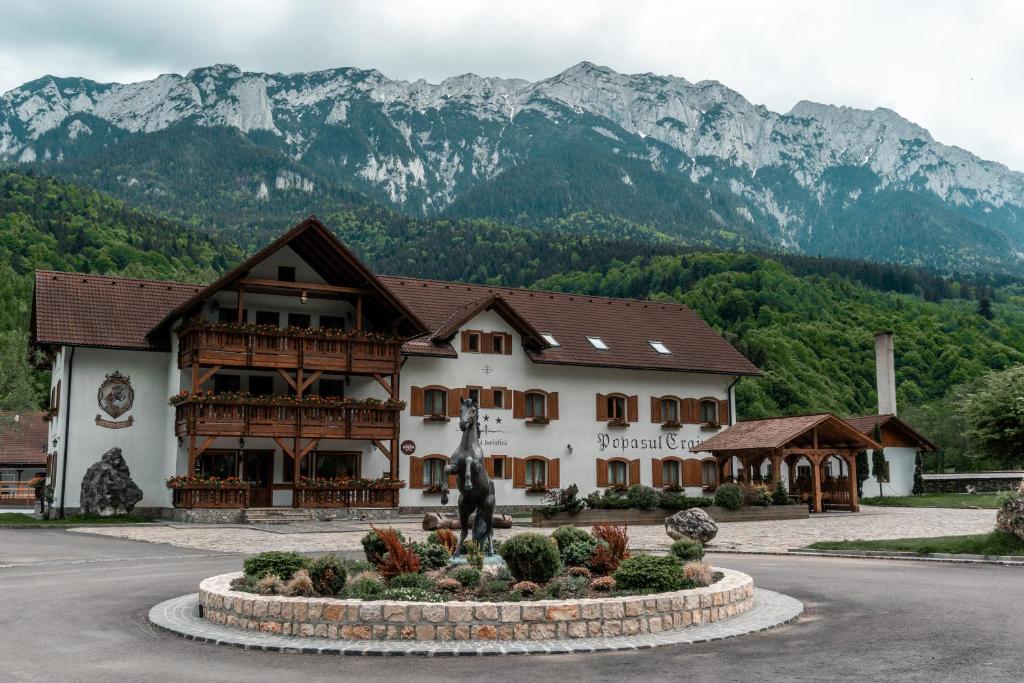 um grande edifício com montanhas ao fundo em Popasul Craiului em Zarnesti