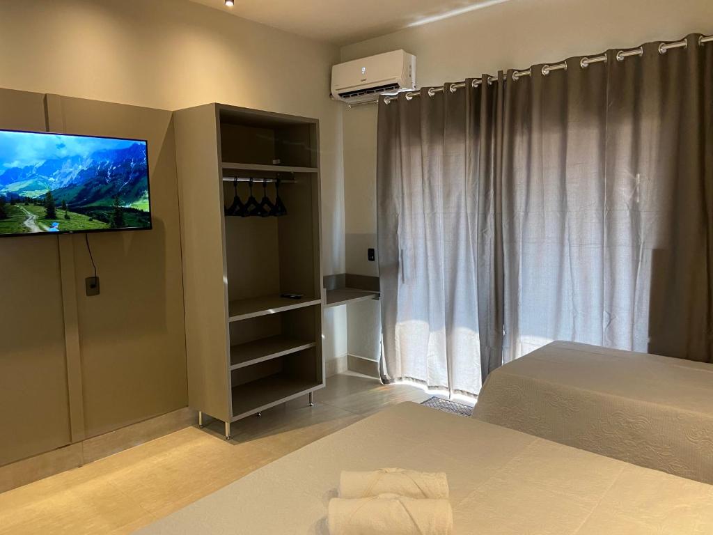 um quarto com uma cama e uma televisão de ecrã plano em Pousada Pôr do Sol em São João Batista do Glória