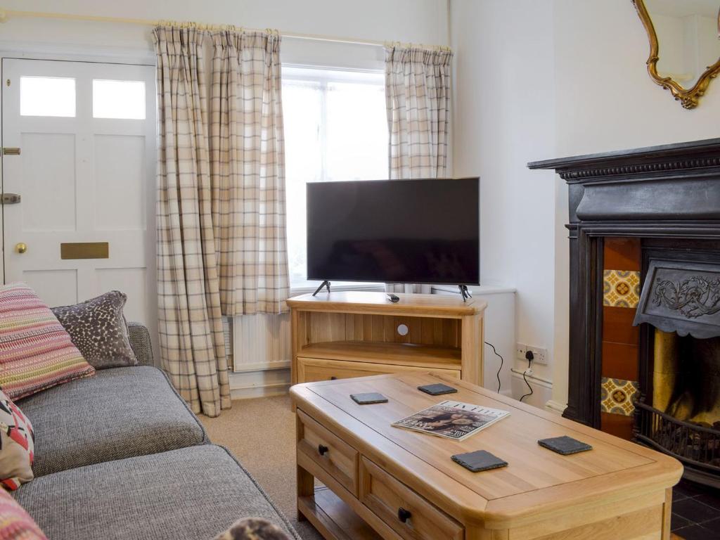 a living room with a couch and a tv and a coffee table at The Cottage in Ledbury