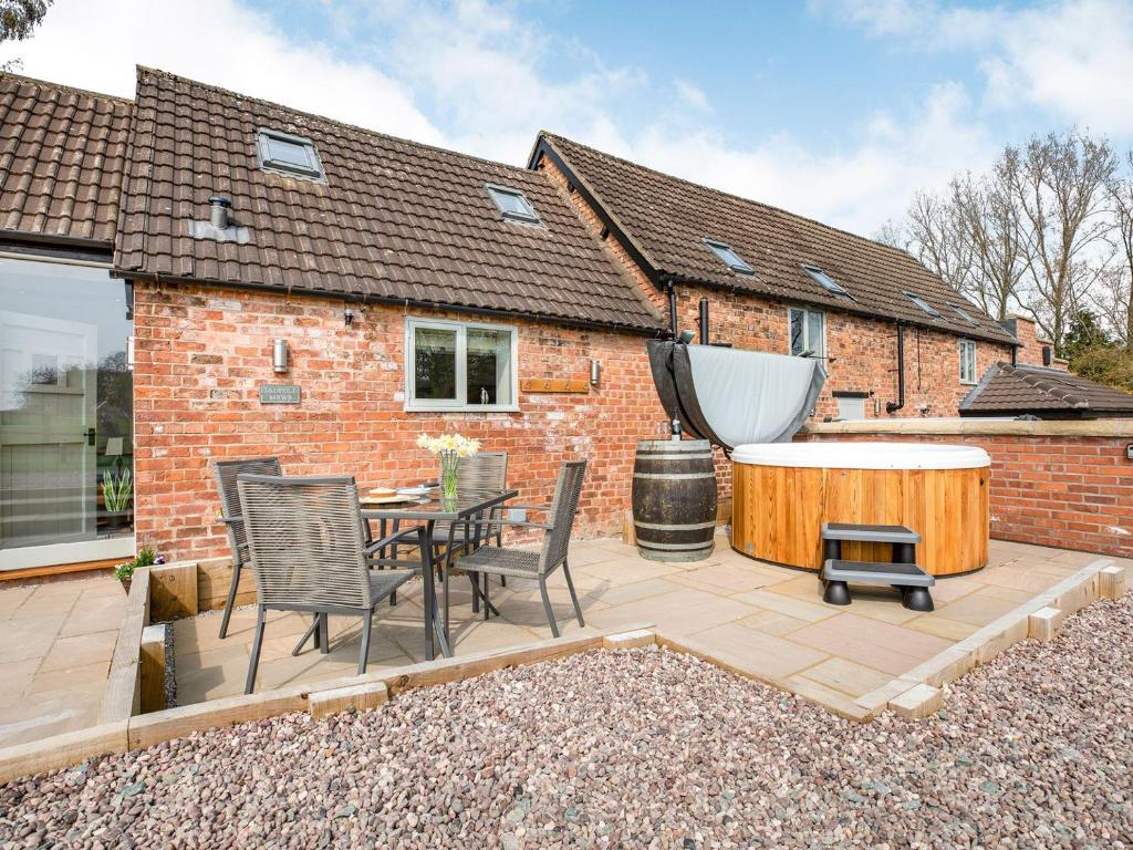 a patio with a table and chairs and a tub at Tadpole Mews At Frog Hall in Tilston
