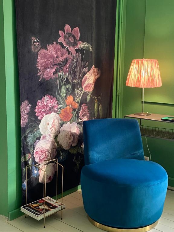 a blue chair in a room with a painting of flowers at Jules&Jim Gästehaus in Linz